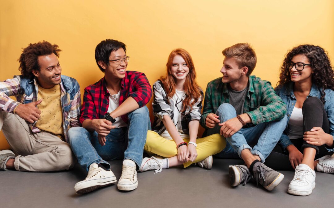 A diverse group of young adults sitting against a wall